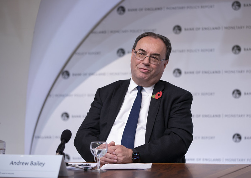Andrew Bailey sits at a desk in front of a microphone, wearing a suit