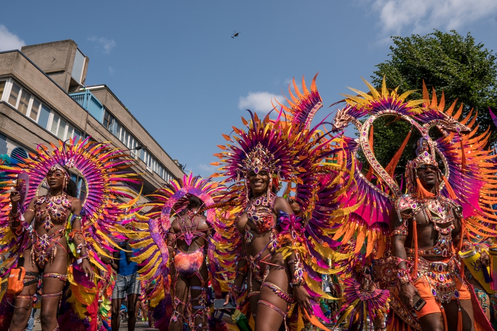 Women in colourful carnival costumes pose at Notting Hill carnival
